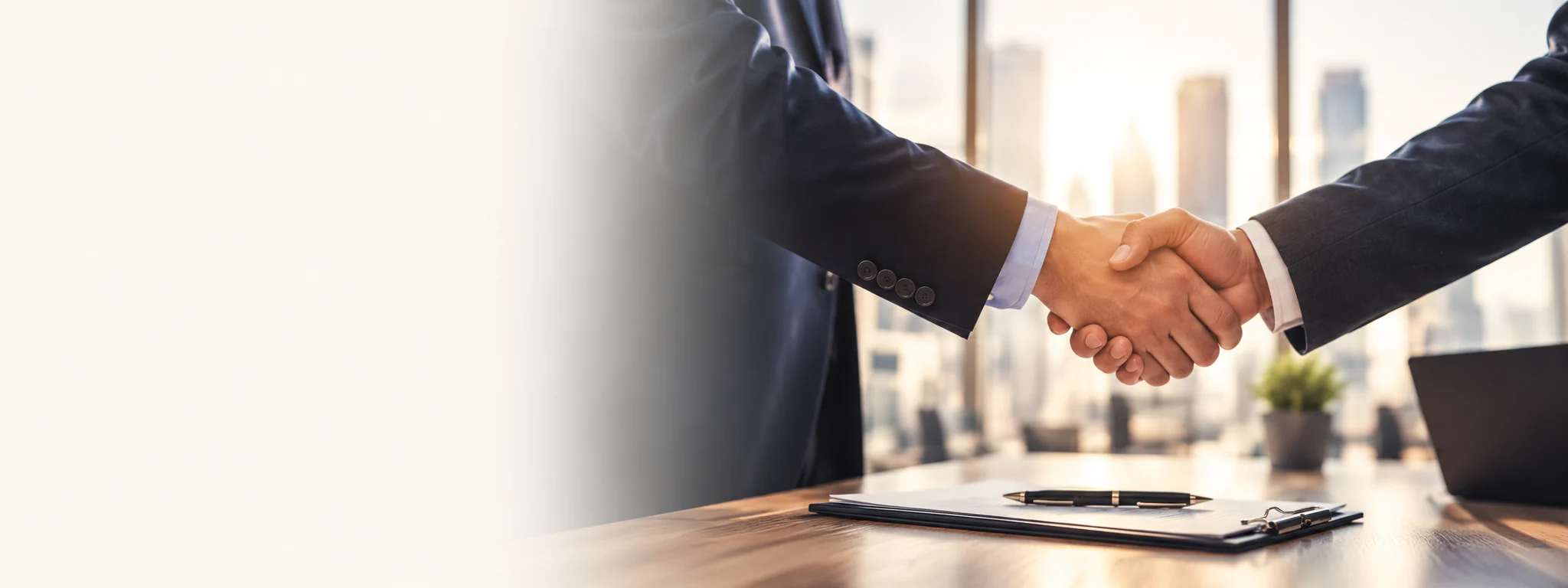 Business partners shaking hands across an office desk